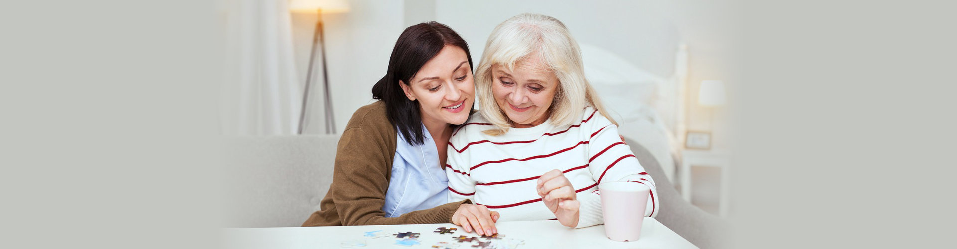 senior women and her caregiver playing a puzzle